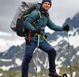 Trekker with a backpack on a snowy mountain trail