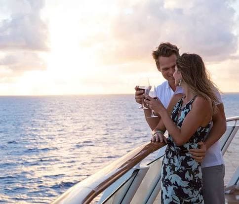 Couple toasting with wine at sunset on a ship deck